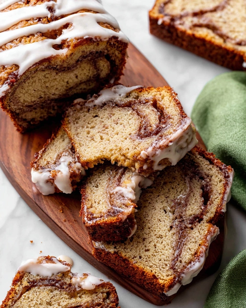 The image shows several slices of a cinnamon swirl banana bread on a small wooden board placed on a white marbled surface. Each slice has a golden brown crust with swirls of darker cinnamon running through its light brown, moist interior. A thick white glaze is drizzled over the top edges of the bread slices, some of it dripping down the sides. There is a small piece broken off one slice, showing a soft texture inside. A green cloth is partly visible on the right side, adding a soft color contrast. Photo taken with an iphone --ar 4:5 --v 7