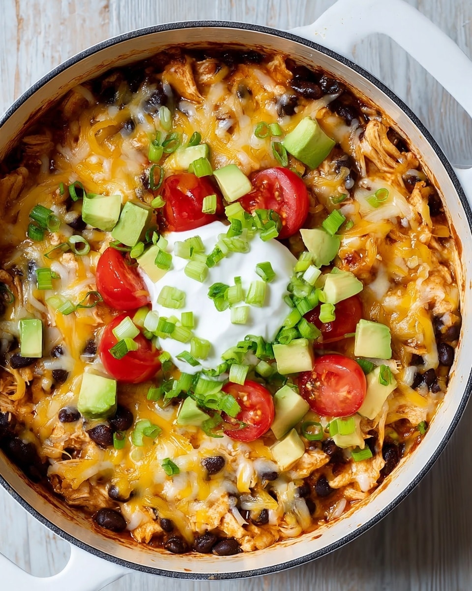 A white round pot filled with a layered dish starting with a base of black beans, topped with shredded melted cheese in white and yellow colors, and pieces of cooked chicken mixed in. On top, there are scattered chopped green onions, small chunks of light green avocado, and halved bright red cherry tomatoes. At the center, there is a dollop of white sour cream, also garnished with small pieces of avocado, cherry tomatoes, and green onions. The pot is placed on a white marbled textured surface. Photo taken with an iphone --ar 4:5 --v 7