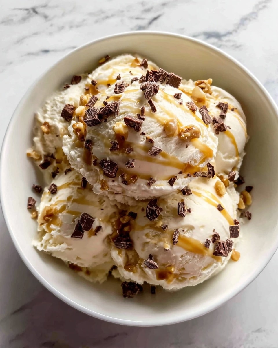 A white bowl filled with three large scoops of creamy, off-white ice cream that has a smooth and slightly fluffy texture. The ice cream is sprinkled generously with small pieces of chocolate and nuts, adding a dark brown and light tan contrast. A thin drizzle of caramel sauce flows softly over the top scoop, giving a glossy amber touch. The bowl is placed on a white marbled surface with soft lighting enhancing the texture and colors. Photo taken with an iphone --ar 4:5 --v 7