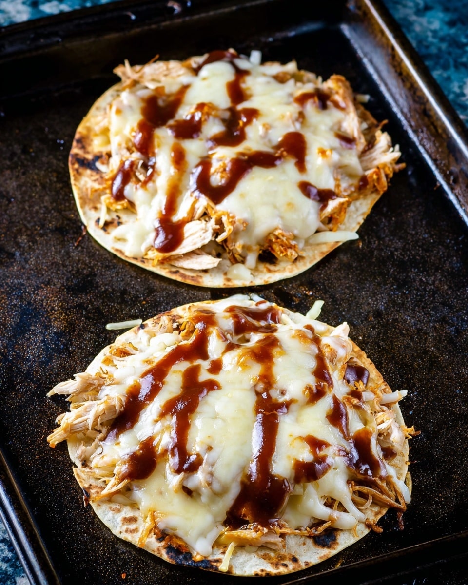 Two small flat tortillas lay on a black baking tray with a white marbled texture surface visible in the background. Each tortilla is topped with a layer of shredded, cooked chicken covered generously with melted, creamy white cheese that has a smooth texture and slight browning at the edges. Drizzled dark brown barbecue sauce is scattered in patches over the cheese, creating contrast and shine. The edges of the tortillas are slightly crispy, with some cheese melted onto the tray. Photo taken with an iphone --ar 4:5 --v 7