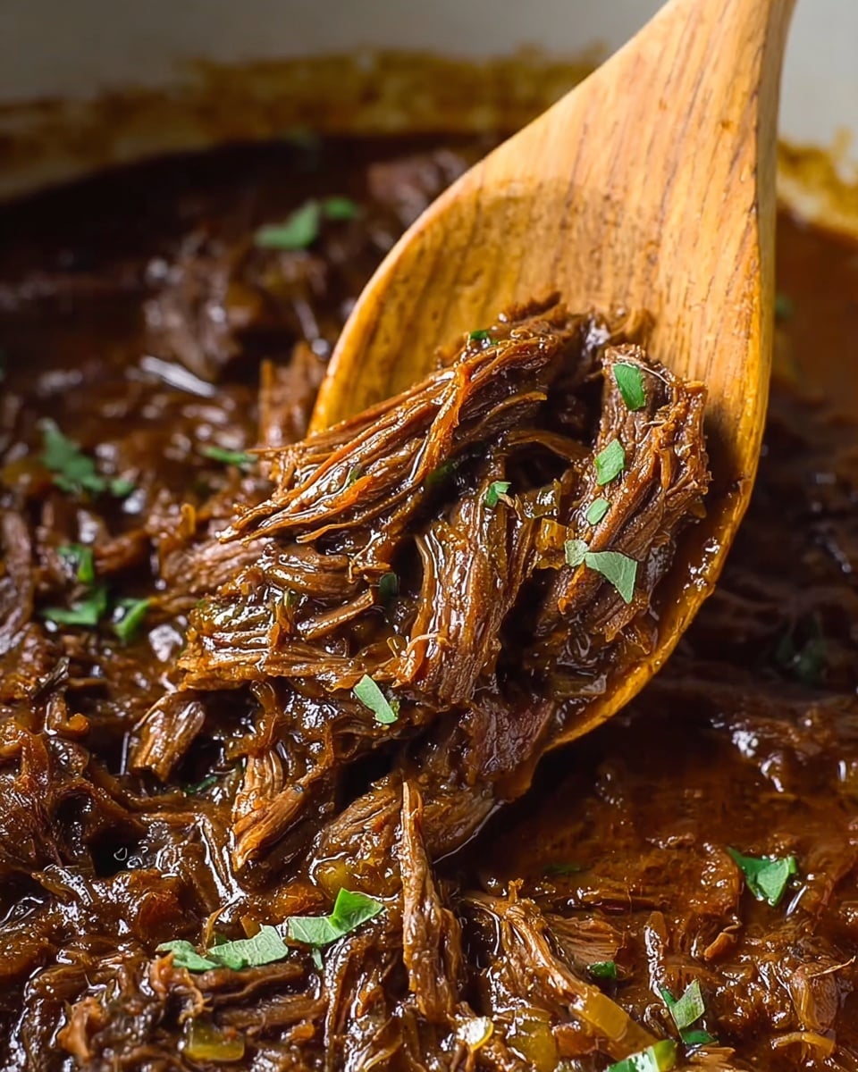 The image shows a close-up of shredded beef cooked in a rich, dark brown sauce with visible pieces of soft onion mixed in. The beef looks tender and juicy with a fibrous texture, and small green herb leaves are scattered on top, adding a fresh color contrast. The beef and sauce fill the background with a glossy, thick liquid layer, while a wooden spoon holds a scoop of the meat above the rest. The photo is focused on the beef’s fibrous and moist texture with bright lighting that enhances the glossy sauce. The background is a white marbled texture. photo taken with an iphone --ar 4:5 --v 7